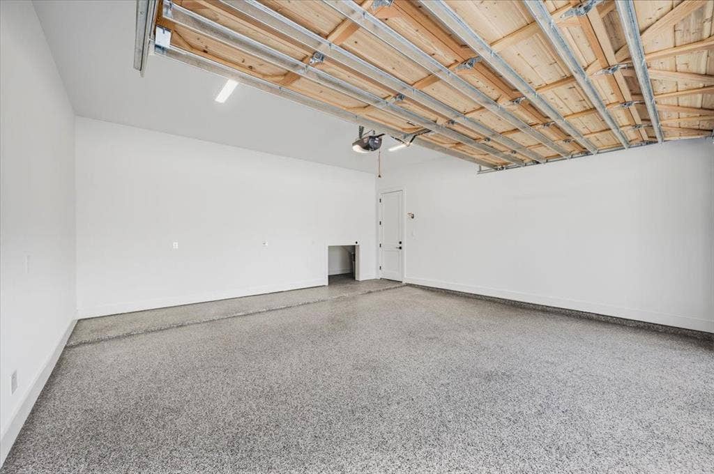 4320 Concho Street, Dallas, TX 75206 Spacious garage featuring a durable epoxy floor coating, white painted walls, and exposed ceiling joists