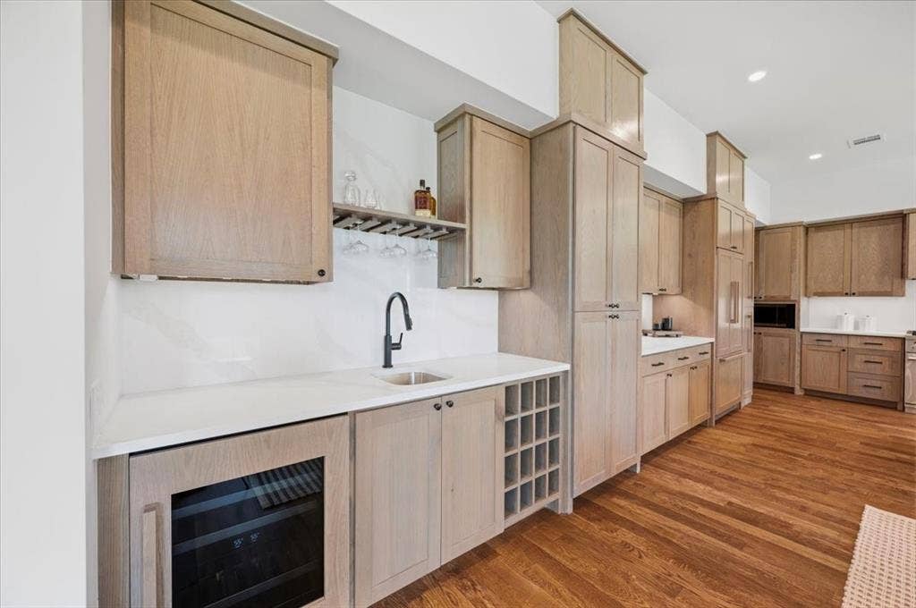 4320 Concho Street, Dallas, TX 75206 Hardwood flooring throughout, full-height light wood-finish cabinetry, integrated wine cooler, built-in wine rack, and a dedicated beverage sink with a matte black faucet