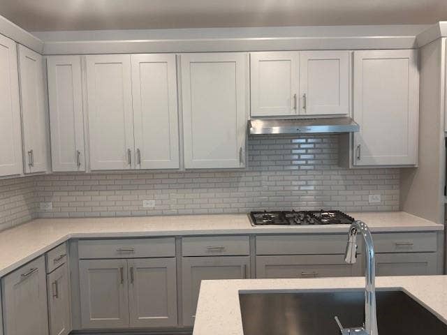 109 North Sky Drive, Celina, TX 75009 Shaker-style cabinetry, subway tile backsplash, stainless steel range hood, built-in gas cooktop, and undermount sink with a pull-down faucet
