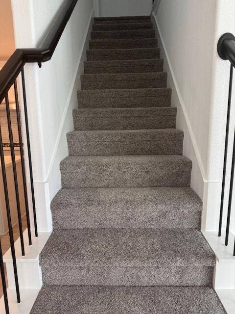 109 North Sky Drive, Celina, TX 75009 Staircase featuring dark gray carpet, white risers, and black metal balusters with a dark wood-finish handrail