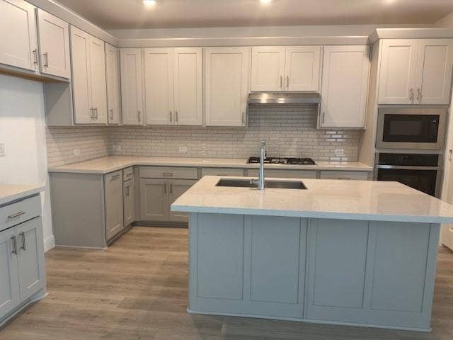 109 North Sky Drive, Celina, TX 75009 Kitchen featuring light gray cabinetry, light-toned countertops, a subway tile backsplash, stainless steel appliances, and wood-finish flooring