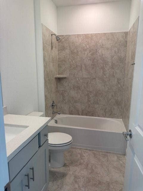 109 North Sky Drive, Celina, TX 75009 Bathroom featuring a built-in bathtub with shower, tiled surround, toilet, and vanity with an integrated sink and chrome hardware
