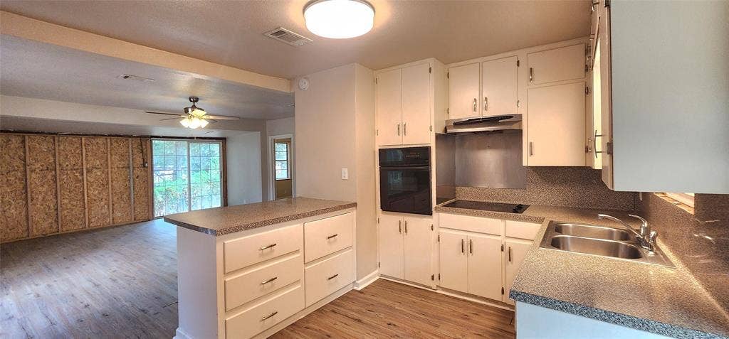 2016 Gavin Road, Tool, TX 75143 Kitchen featuring white cabinetry, built-in double ovens, a flat-top electric range, a double basin stainless steel sink, and vinyl flooring