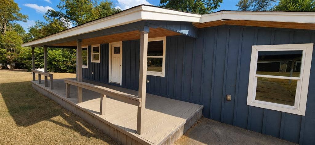2016 Gavin Road, Tool, TX 75143 Exterior featuring dark blue vertical siding, white trim, a covered porch with composite decking, and white-framed windows
