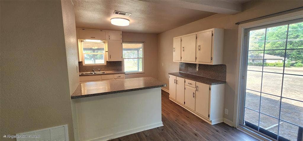 2016 Gavin Road, Tool, TX 75143 Kitchen featuring white cabinetry, a central island with a stone-finish countertop, vinyl flooring, and a sliding glass door