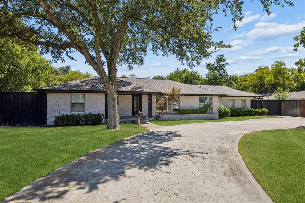5610 Forest Lane, Dallas, TX 75230 White brick facade with dark trim, mature trees, and a concrete driveway