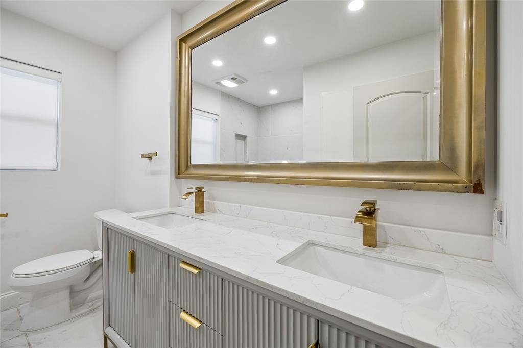 5610 Forest Lane, Dallas, TX 75230 Dual vanity with integrated rectangular sinks, a light-toned countertop, and gold-finish faucets