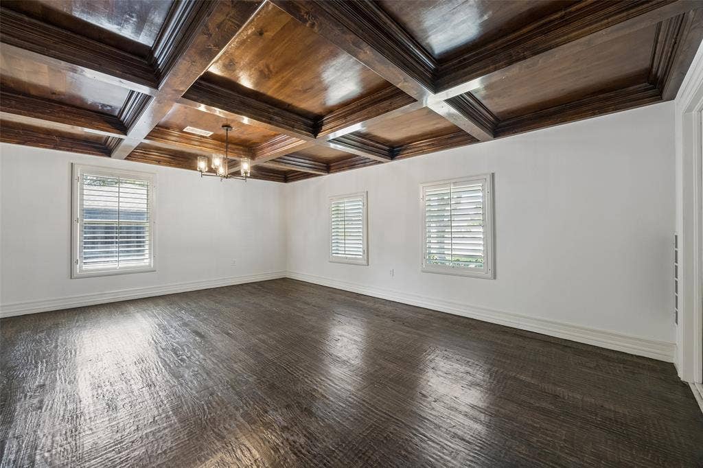 5610 Forest Lane, Dallas, TX 75230 Coffered wood-finish ceiling with an attached light fixture, white walls, wood-finish flooring, and two windows with plantation shutters