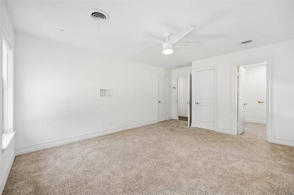 5610 Forest Lane, Dallas, TX 75230 Carpeted flooring, white walls, white ceiling fan with integrated lighting, multiple white panel doors, and a window for natural light