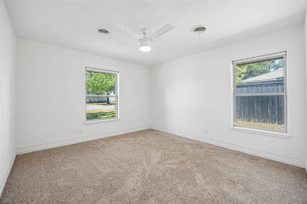 5610 Forest Lane, Dallas, TX 75230 Neutral wall finishes with a ceiling fan light fixture, two windows, and carpeting
