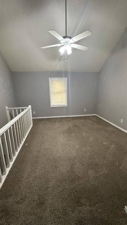 Vaulted ceiling with a ceiling fan light fixture, gray painted walls, and dark brown carpeting