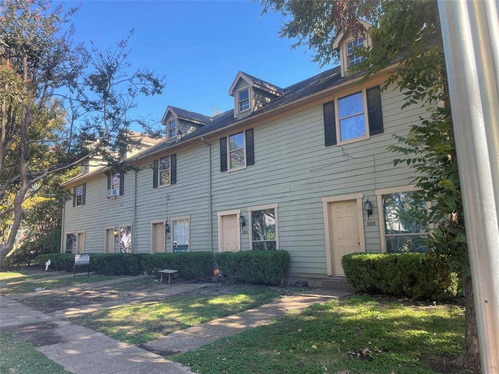 Multi-unit residential exterior featuring lap siding, peaked dormer windows, shuttered window accents, and individual entryways