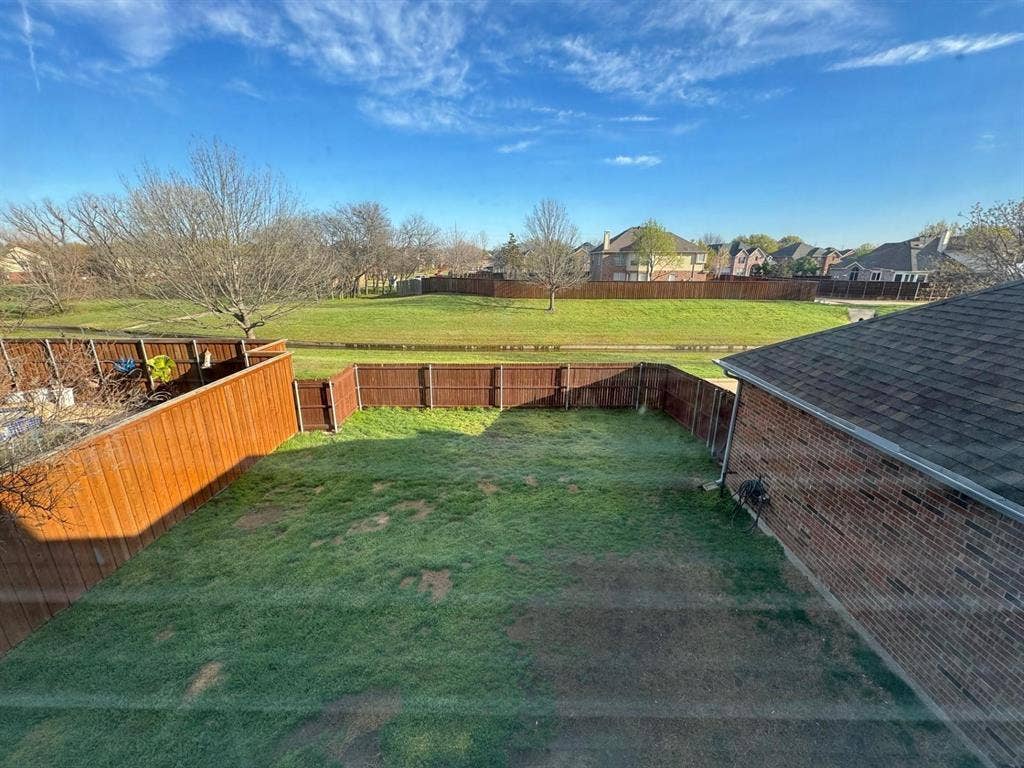 4531 Oak Shores Drive, Plano, TX 75024 Expansive backyard featuring a manicured lawn, wood fencing, and a brick exterior