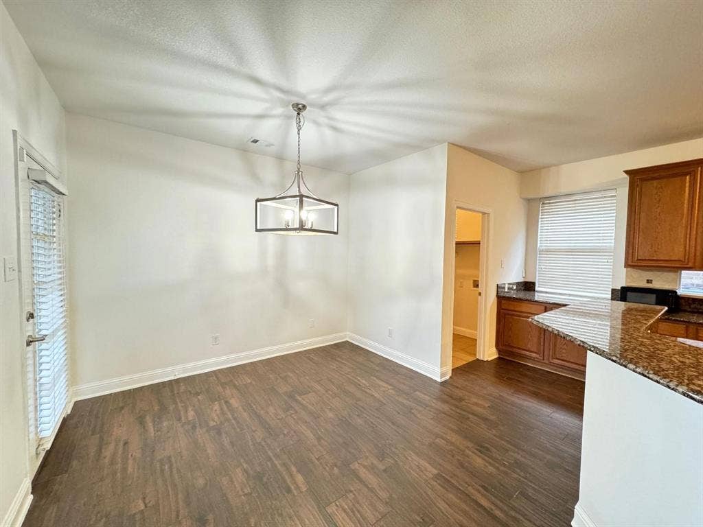 4531 Oak Shores Drive, Plano, TX 75024 Wood-finish flooring, contemporary chandelier, white walls, and dark wood cabinetry with stone countertops