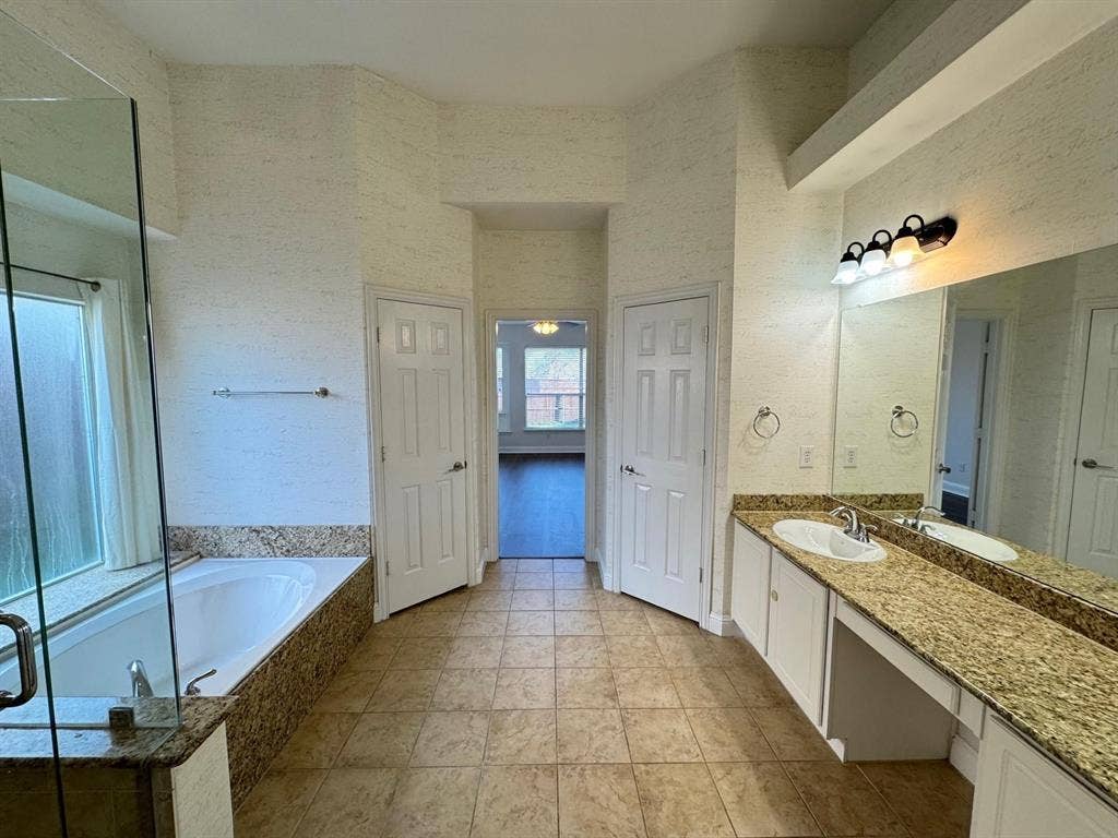 4531 Oak Shores Drive, Plano, TX 75024 Expansive bathroom featuring a built-in soaking tub, glass-enclosed shower, dual vanity with undermount sinks, and a large wall mirror