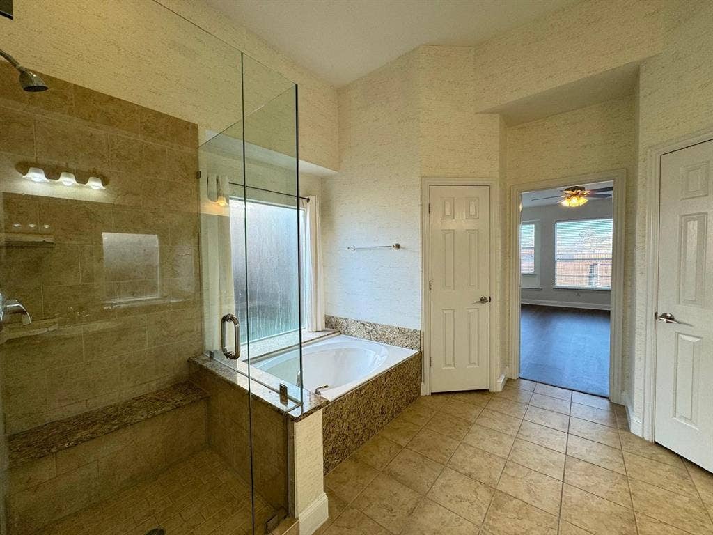 4531 Oak Shores Drive, Plano, TX 75024 Tiled flooring and a built-in soaking tub complement the glass-enclosed shower, featuring a built-in bench and tiled walls