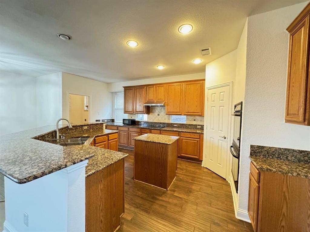 4531 Oak Shores Drive, Plano, TX 75024 Kitchen featuring wood-finish flooring, granite countertops, wood cabinetry, a built-in oven, and recessed lighting