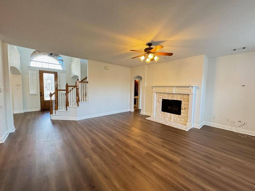 4531 Oak Shores Drive, Plano, TX 75024 Wood-finish flooring throughout, featuring a fireplace with a stone surround and mantle, and a ceiling fan with integrated lighting