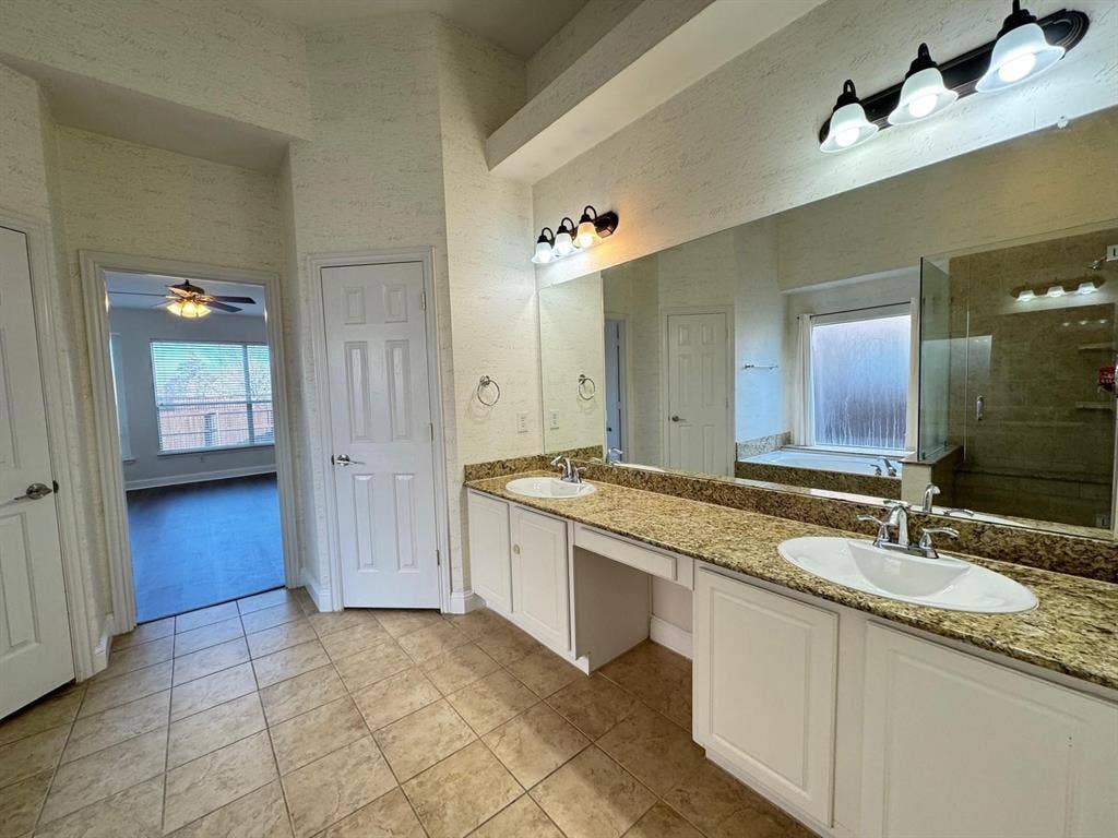 4531 Oak Shores Drive, Plano, TX 75024 Dual vanity with undermount sinks, stone-finish countertops, and an expansive wall mirror