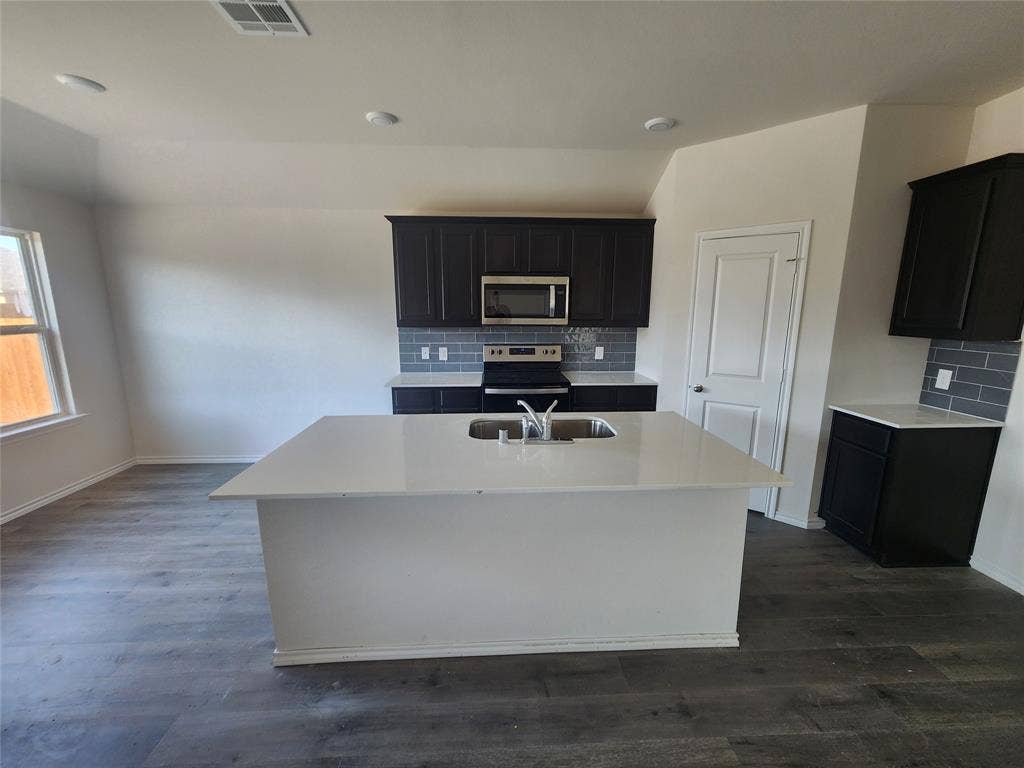 1302 Breezy Oak Drive, Nevada, TX 75173 Spacious kitchen featuring dark cabinetry, subway tile backsplash, white countertops, and wood-finish flooring