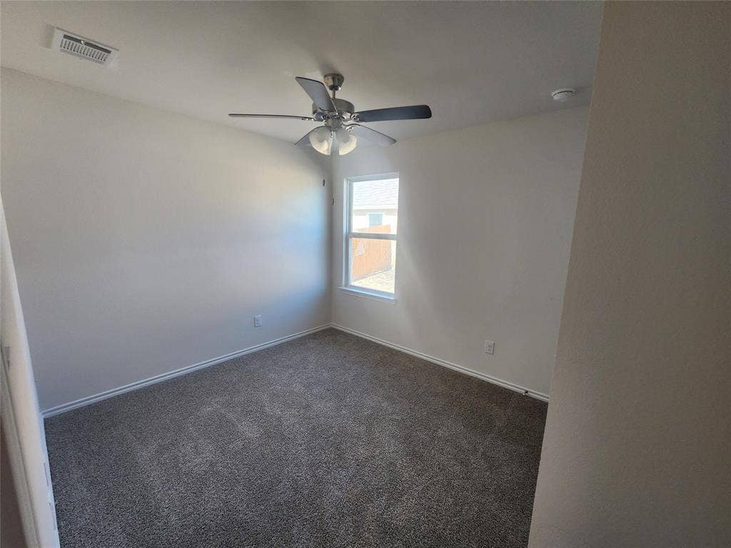 1302 Breezy Oak Drive, Nevada, TX 75173 Neutral wall paint, ceiling fan with light fixture, window with white frame, and gray carpet flooring