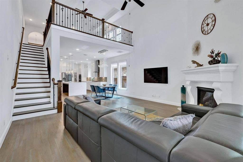 625 Quarter Horse Lane, Frisco, TX 75036 Two-story living space with a fireplace, a second-story balcony, wood-finish flooring, and a staircase with dark wood-finish treads and white risers