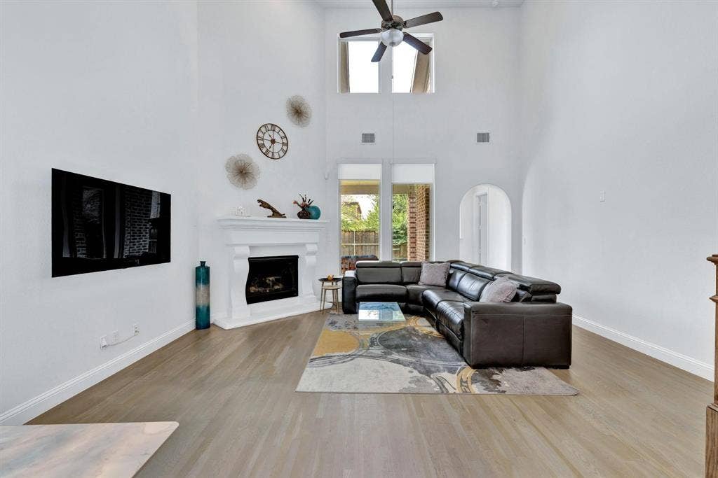 625 Quarter Horse Lane, Frisco, TX 75036 Soaring ceilings, corner fireplace with mantel, arched doorways, wood-finish flooring, and a ceiling fan