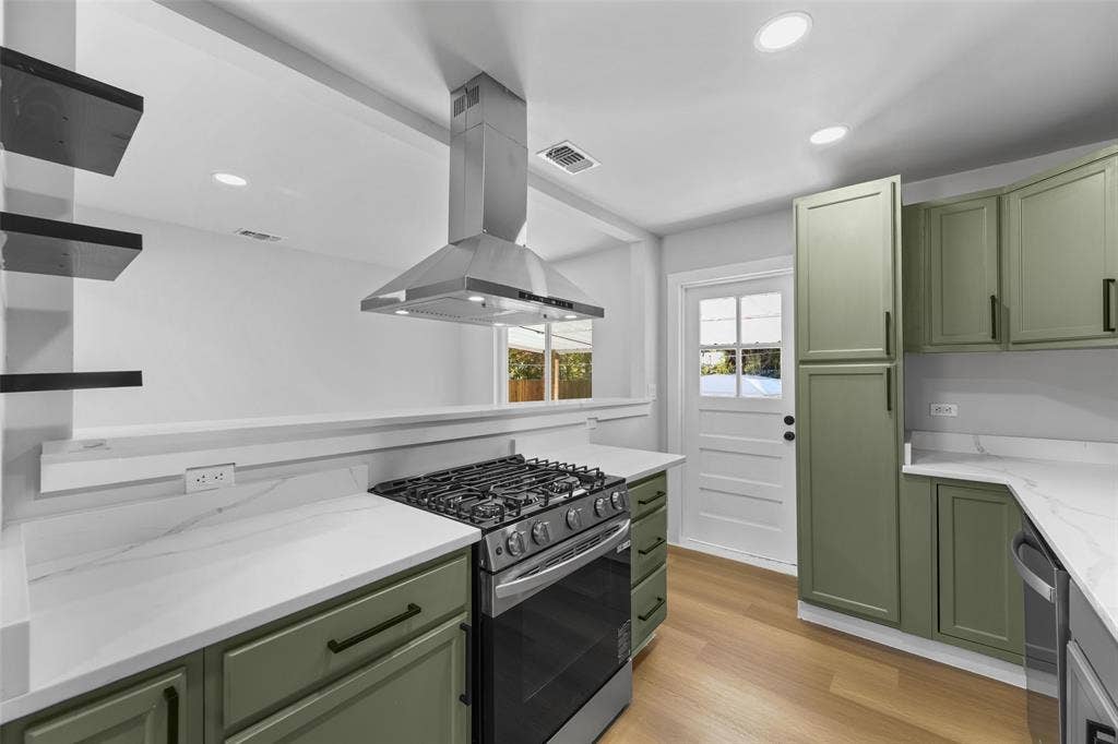 Kitchen featuring sage green cabinetry, stainless steel range with overhead hood, white countertops, wood-finish flooring, and recessed lighting