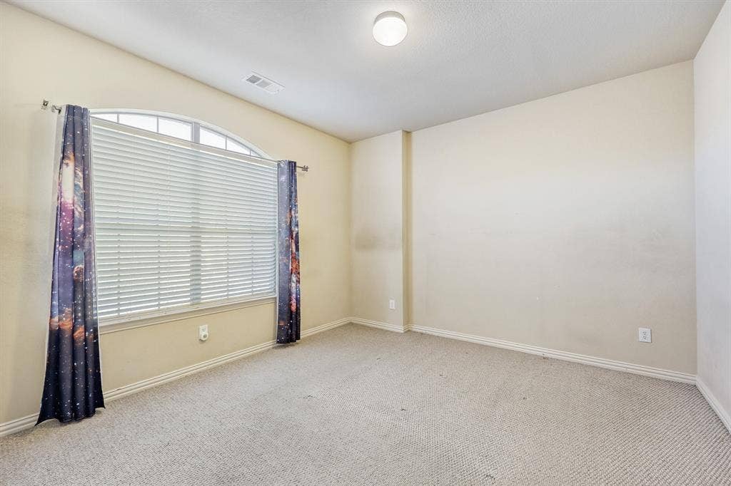 1012 Surrey Drive, DeSoto, TX 75115 Arched window with blinds, vaulted ceiling, and neutral carpet flooring