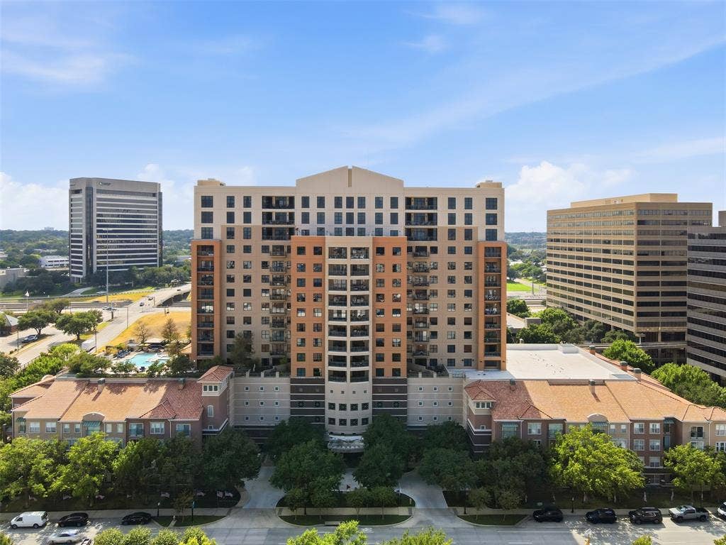330 Las Colinas Boulevard E, #1216, Irving, TX 75039 High-rise building with multiple balconies, a ground-level swimming pool, and surrounding mature trees