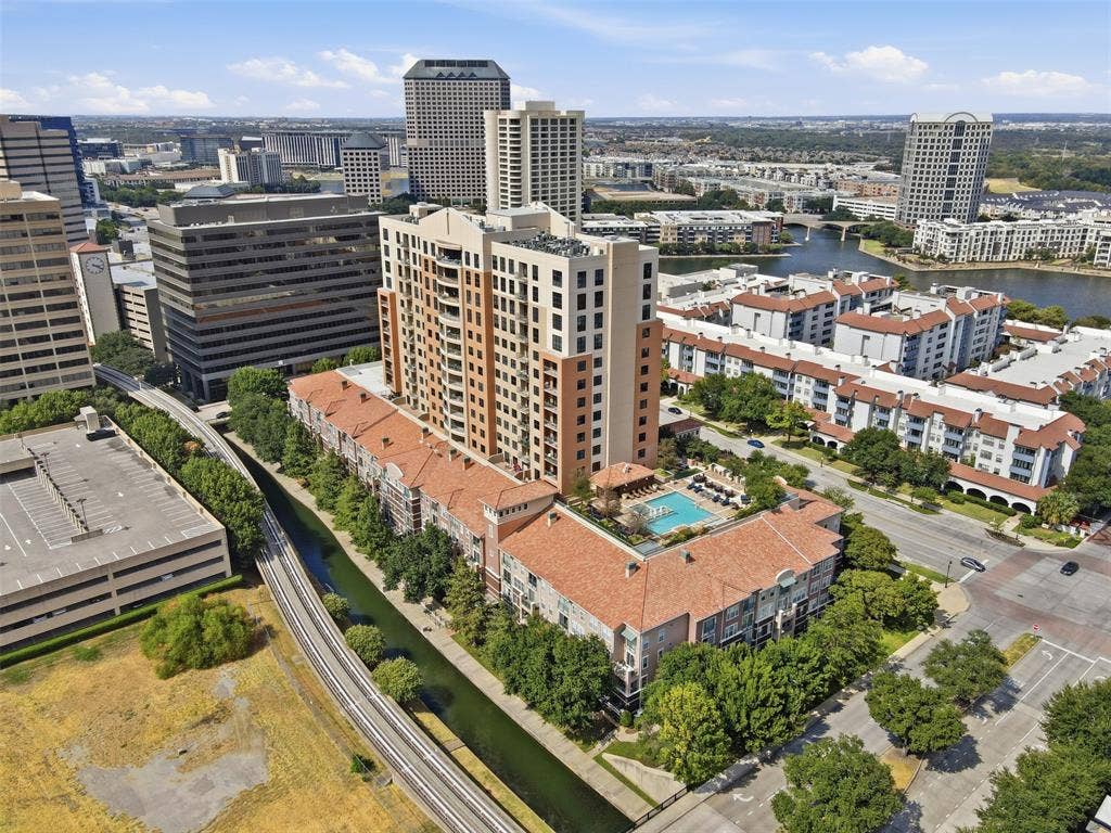 330 Las Colinas Boulevard E, #1216, Irving, TX 75039 High-rise residential building with a tiled roof lower level, outdoor swimming pool, and surrounding urban landscape