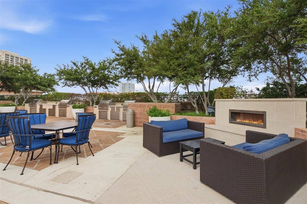 330 Las Colinas Boulevard E, #1216, Irving, TX 75039 Expansive outdoor patio featuring multiple built-in grilling stations, a gas fireplace, and mature trees