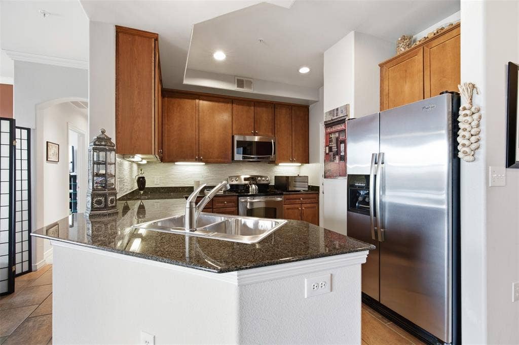 330 Las Colinas Boulevard E, #1216, Irving, TX 75039 Kitchen featuring a dual basin sink, stainless steel appliances, wood cabinetry, granite countertops, and recessed lighting