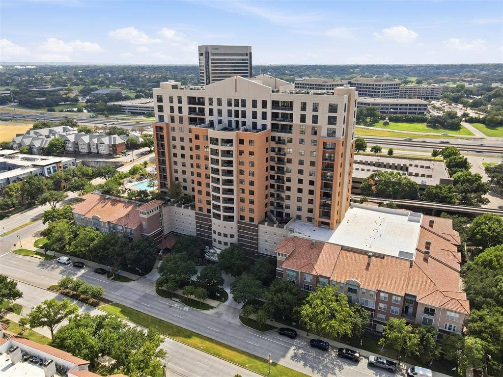 330 Las Colinas Boulevard E, #1216, Irving, TX 75039 High-rise building with multiple balconies, a ground-level swimming pool, and surrounding mature trees