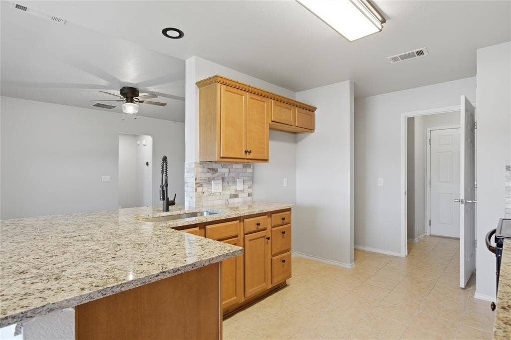 217 Ame Lane, Royse City, TX 75189 Kitchen featuring light wood cabinetry, stone countertops, a stainless steel sink with a matte black faucet, and a tiled backsplash