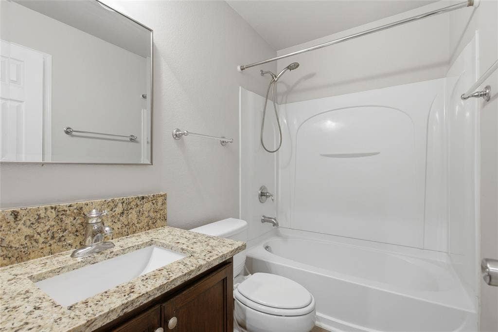 217 Ame Lane, Royse City, TX 75189 Bathroom featuring a vanity with a granite-look countertop, integrated sink, chrome faucet, and a shower-tub combination with a white surround