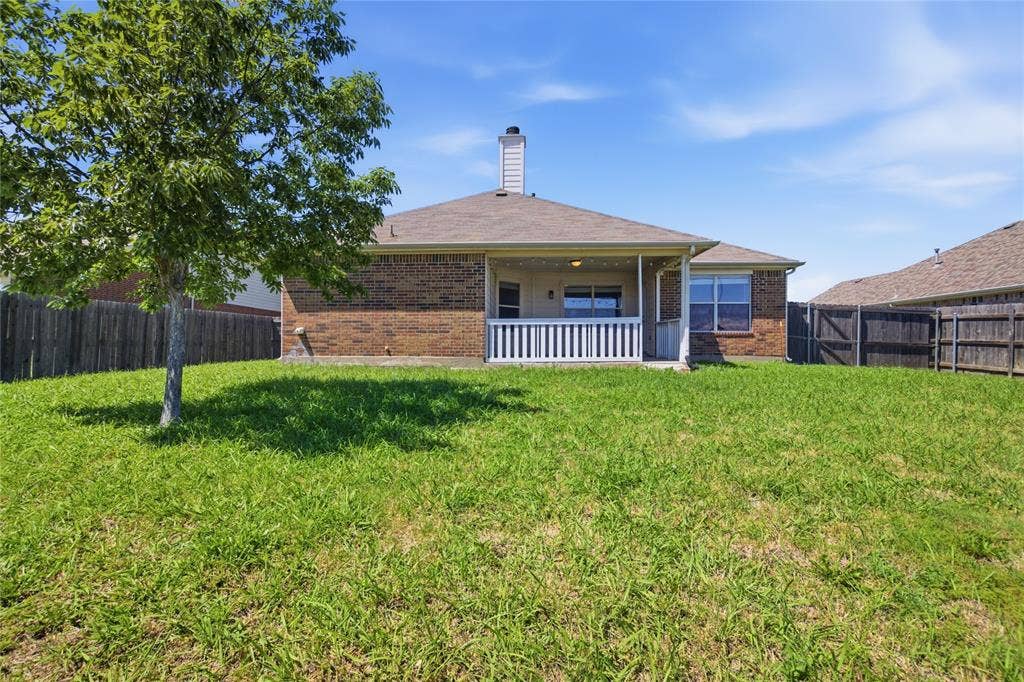 217 Ame Lane, Royse City, TX 75189 Expansive backyard featuring a brick exterior, covered patio with white railing, and wood fencing
