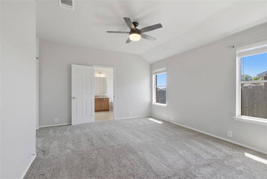 217 Ame Lane, Royse City, TX 75189 Vaulted ceiling, two windows, ceiling fan with integrated lighting, gray carpet flooring, and a white paneled door