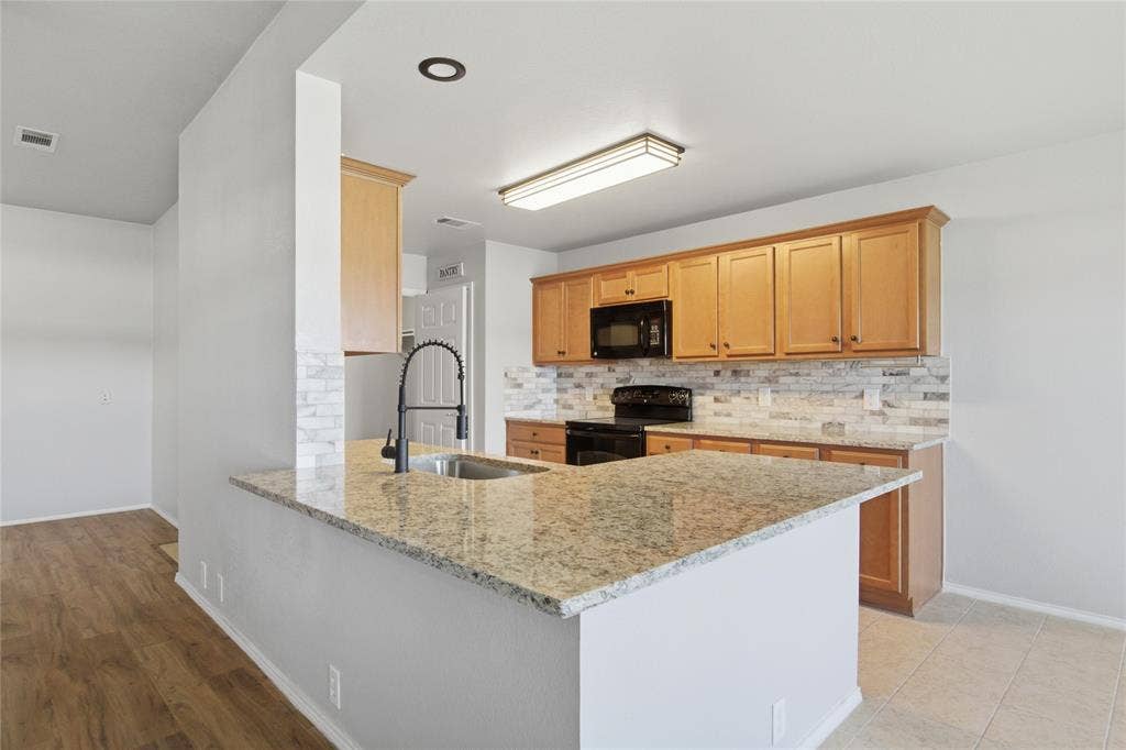 217 Ame Lane, Royse City, TX 75189 Kitchen featuring granite countertops, wood cabinetry, a tile backsplash, and black appliances