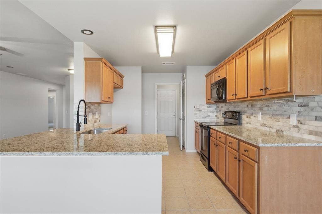 217 Ame Lane, Royse City, TX 75189 Kitchen featuring wood cabinetry, granite countertops, tile backsplash, and a black appliance suite