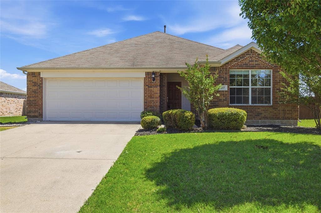 217 Ame Lane, Royse City, TX 75189 Brick exterior with a white garage door, concrete driveway, and established landscaping