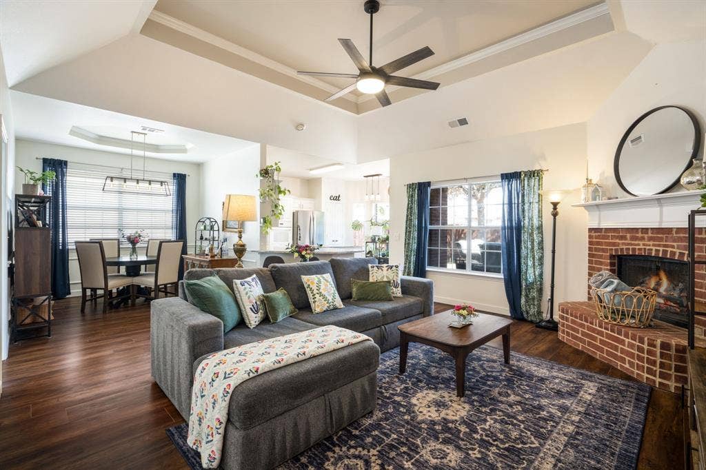 11414 Promenade Road, Frisco, TX 75035 Tray ceiling with a ceiling fan, brick-surround fireplace with a white mantel, and wood-finish flooring