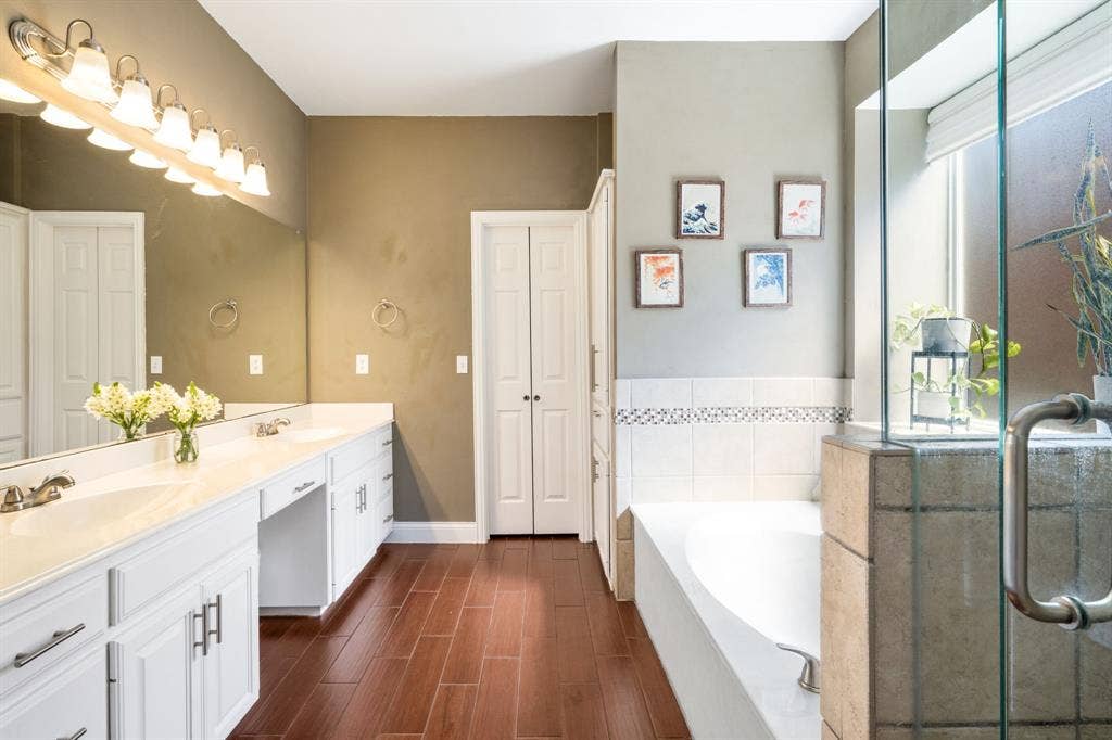 11414 Promenade Road, Frisco, TX 75035 Dual vanities with white cabinetry and integrated sinks, a large soaking tub, and a separate glass-enclosed shower