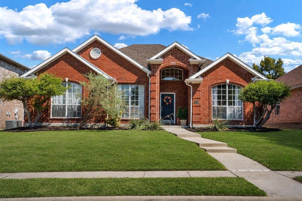 11414 Promenade Road, Frisco, TX 75035 Red brick facade with arched windows, a dark entry door, and a concrete walk