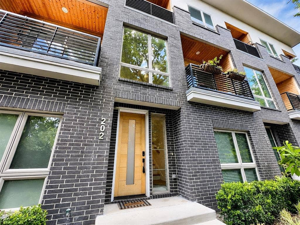 2620 Valley View Lane, #202, Farmers Branch, TX 75234 Modern exterior featuring dark brick, a light wood-finish entry door with a frosted glass insert, and a side light