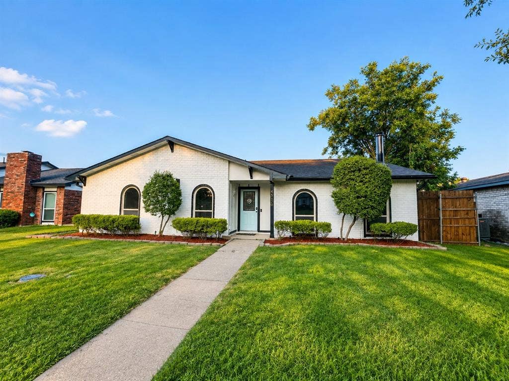 4316 Woodbluff Drive, Mesquite, TX 75150 White brick exterior with black trim, arched windows, and a light blue front door