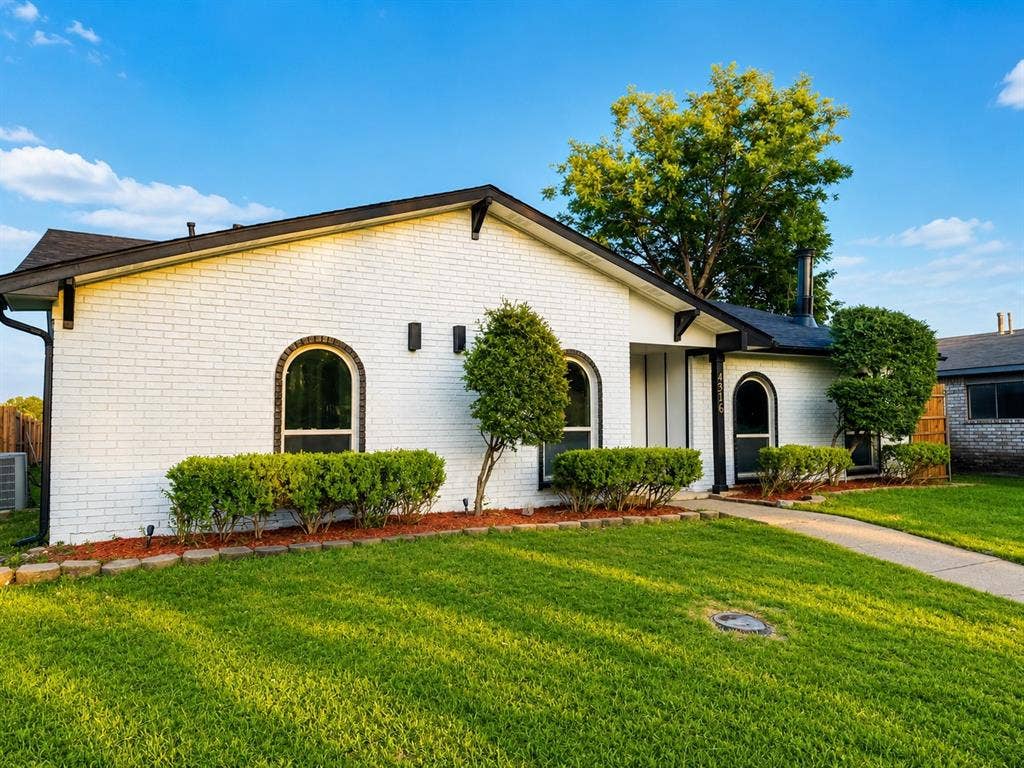 4316 Woodbluff Drive, Mesquite, TX 75150 White brick exterior with black trim, arched windows, and a concrete pathway