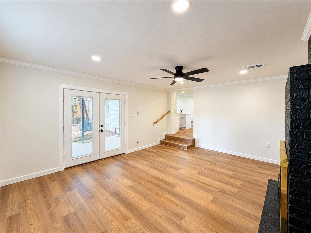 1737 Alta Vista Street, Mesquite, TX 75149 Black painted brick fireplace with integrated hearth, wood-finish flooring, recessed lighting, matte black ceiling fan, and double glass-paned doors