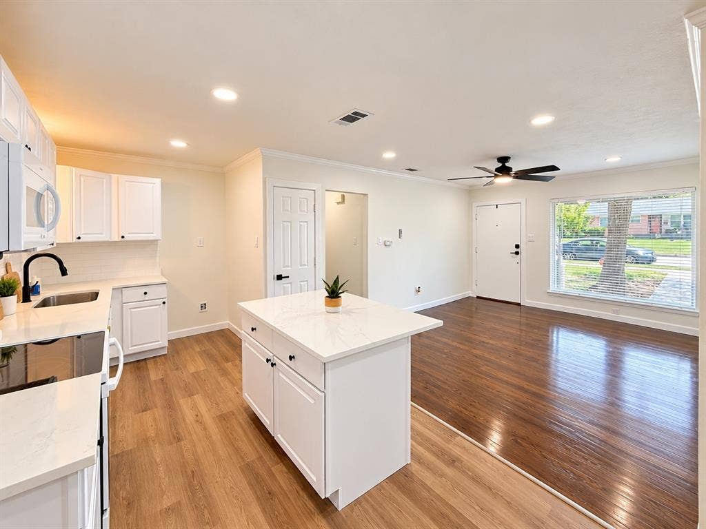 1737 Alta Vista Street, Mesquite, TX 75149 Kitchen featuring a central island with a solid surface countertop, white shaker-style cabinetry, recessed ceiling lighting, wood-finish flooring, and a picture window