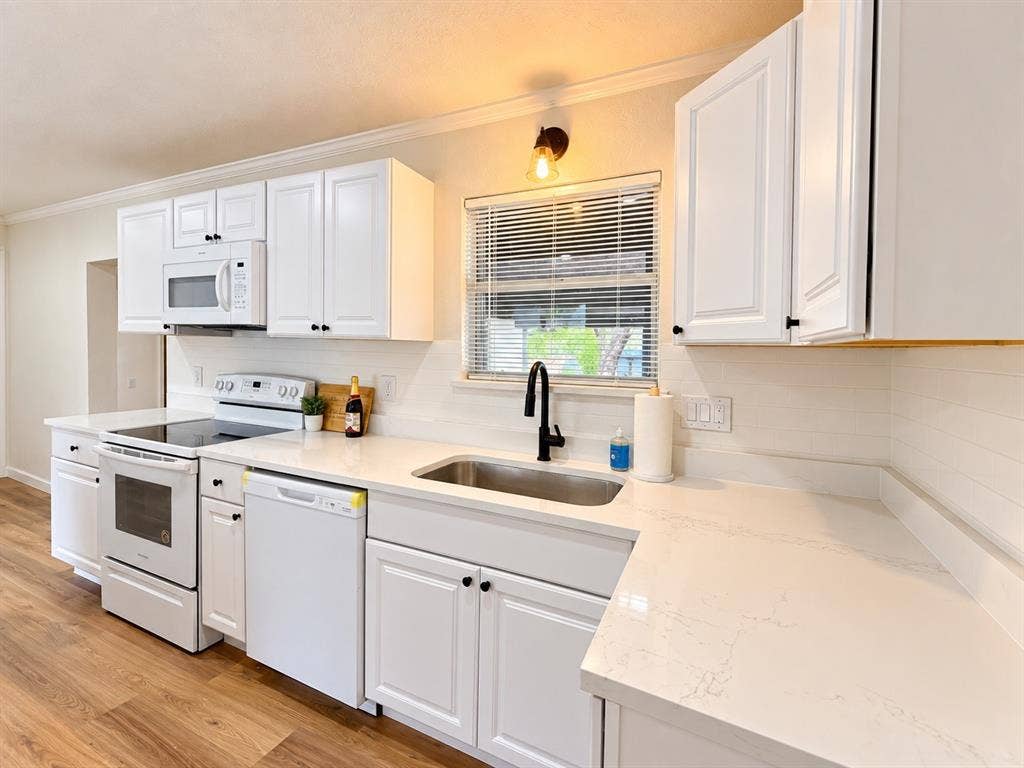 1737 Alta Vista Street, Mesquite, TX 75149 Kitchen featuring white cabinetry, solid-surface countertops, wood-finish flooring, stainless steel undermount sink with a matte black faucet, and white appliances